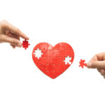 Two people put together a heart-shaped puzzle. The concept of building love relationships.